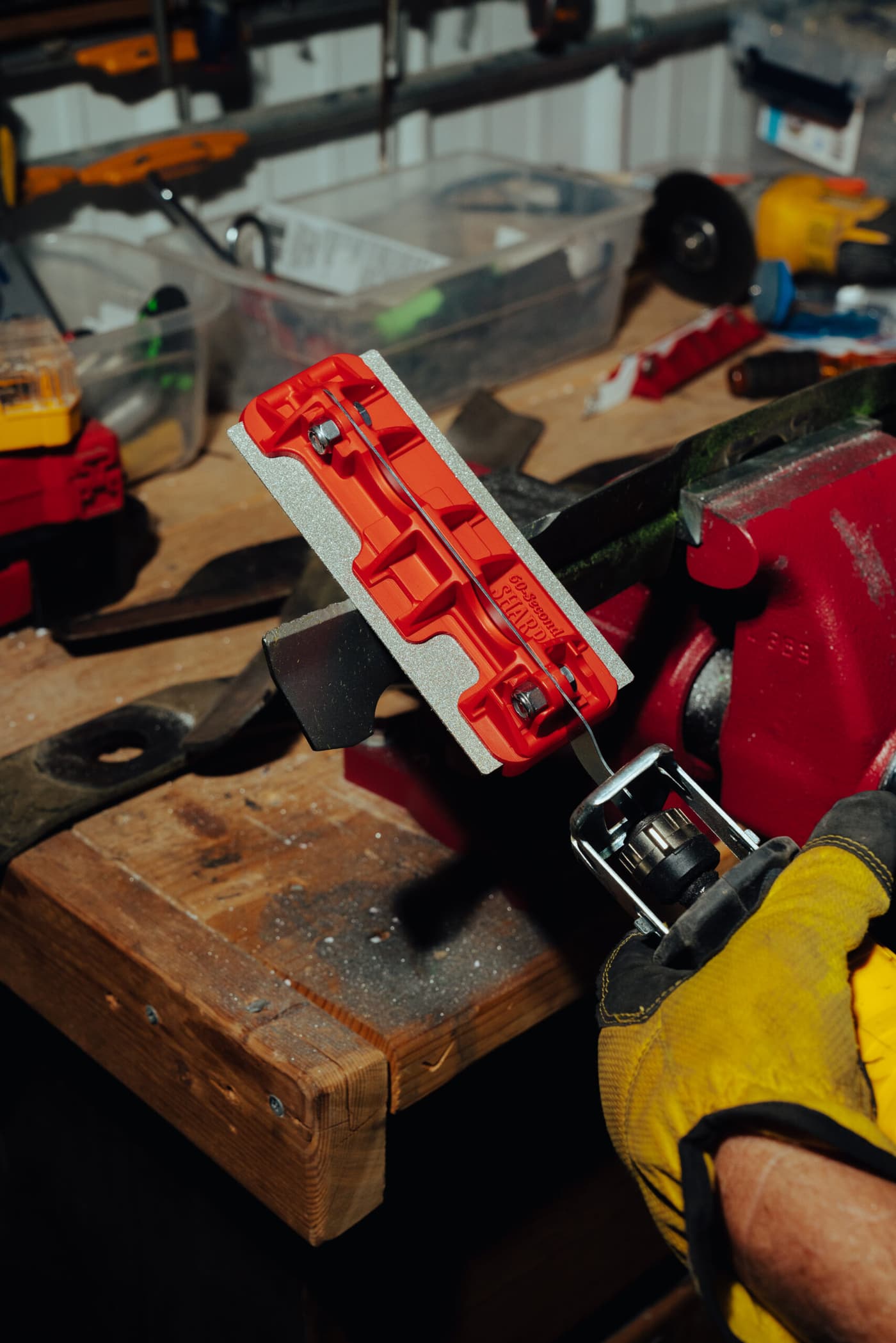 60 Seconds Sharp tool clamped in a workbench vise next to a sharpened mower blade